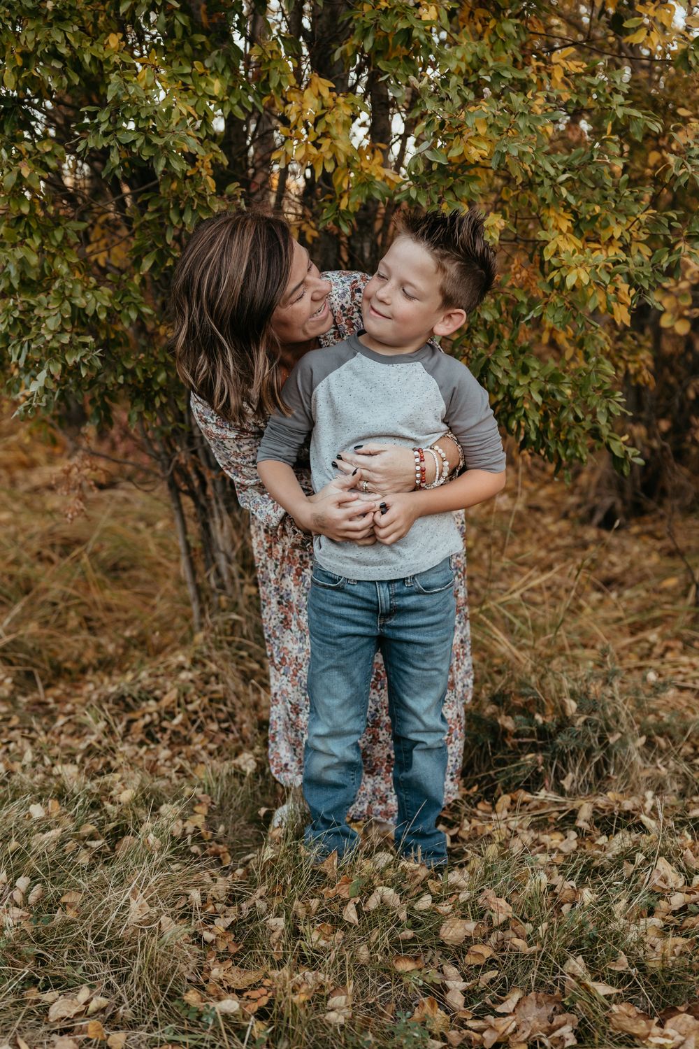 Candid autumn outdoor photoshoot in a wooded setting with fallen leaves.