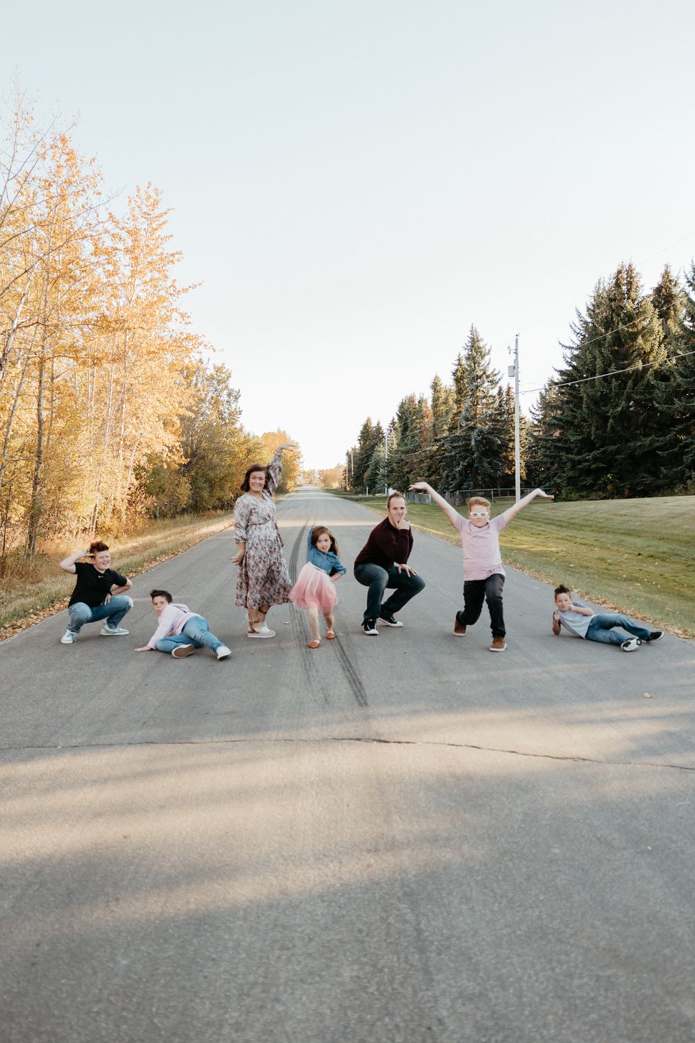 Playful group poses lying down on a paved path during golden hour.