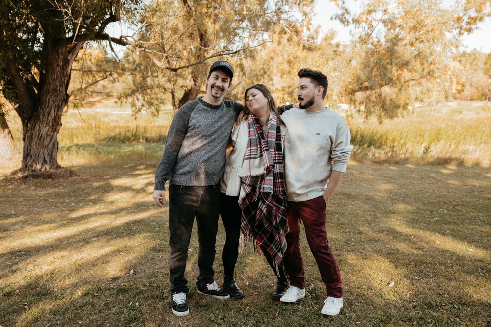 Group photo session in a park with people wearing coordinated casual attire against autumn trees.