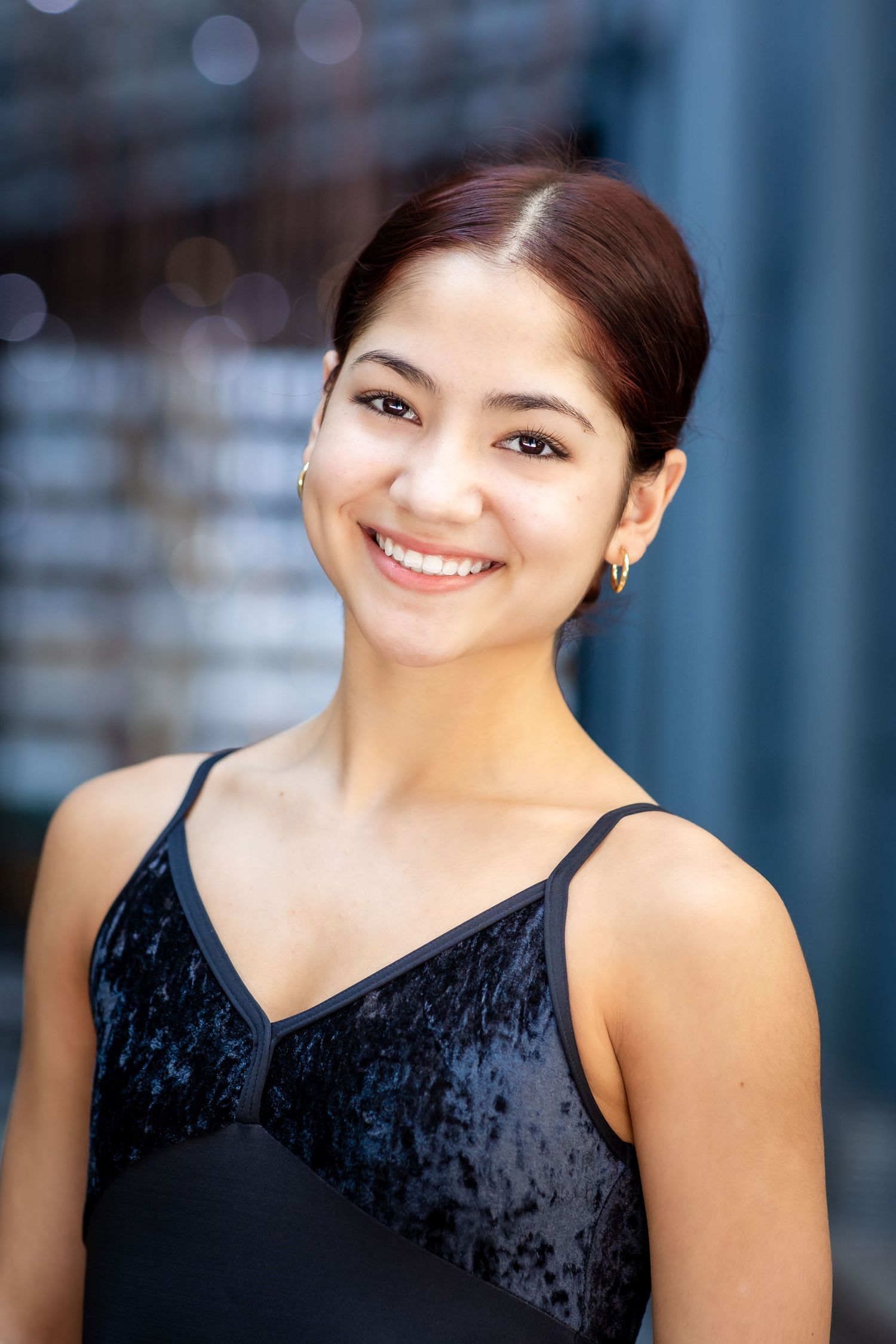Professional headshot with velvet black dance attire against blurred background.