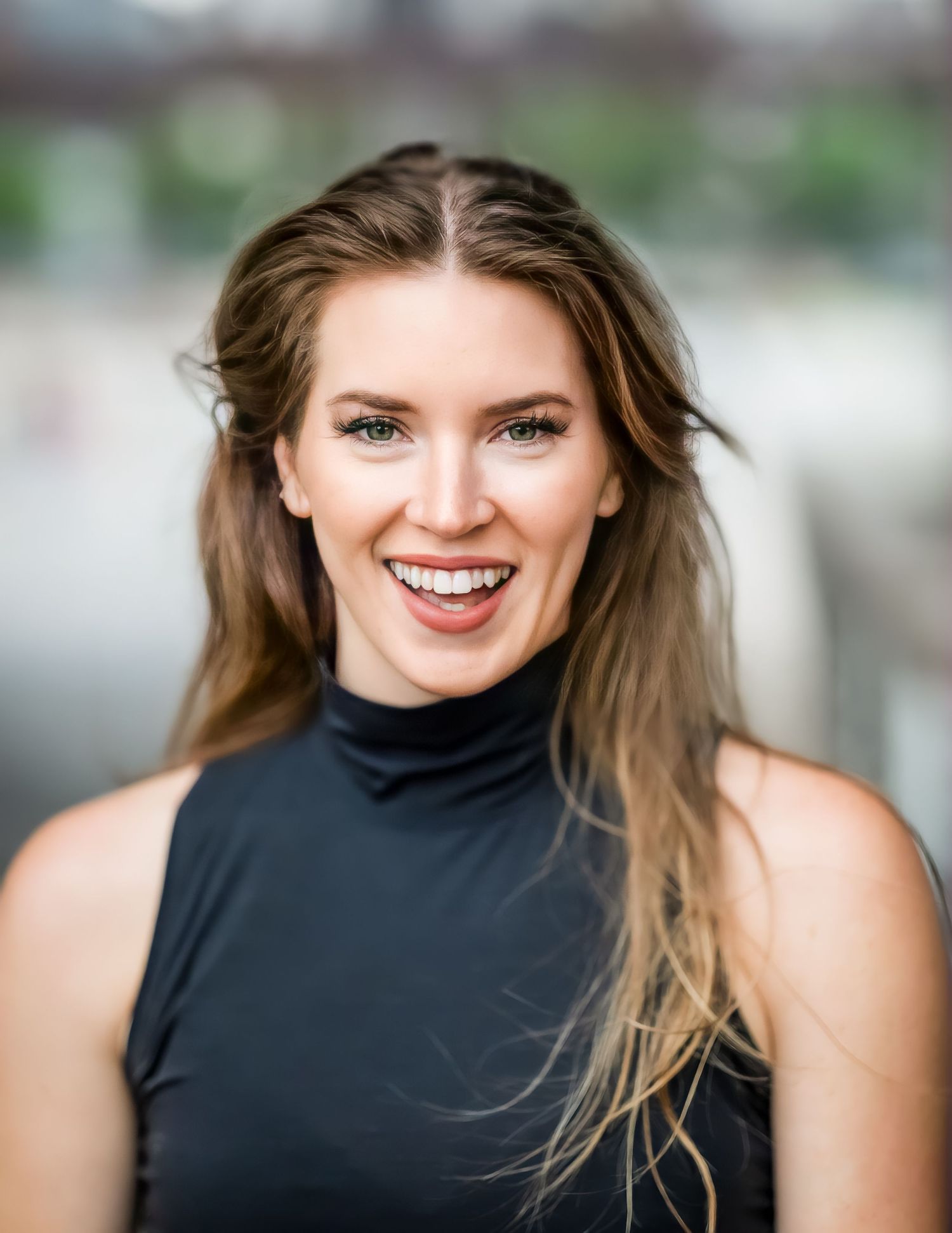 Portrait of a person in a black turtleneck top with natural makeup and flowing hair.