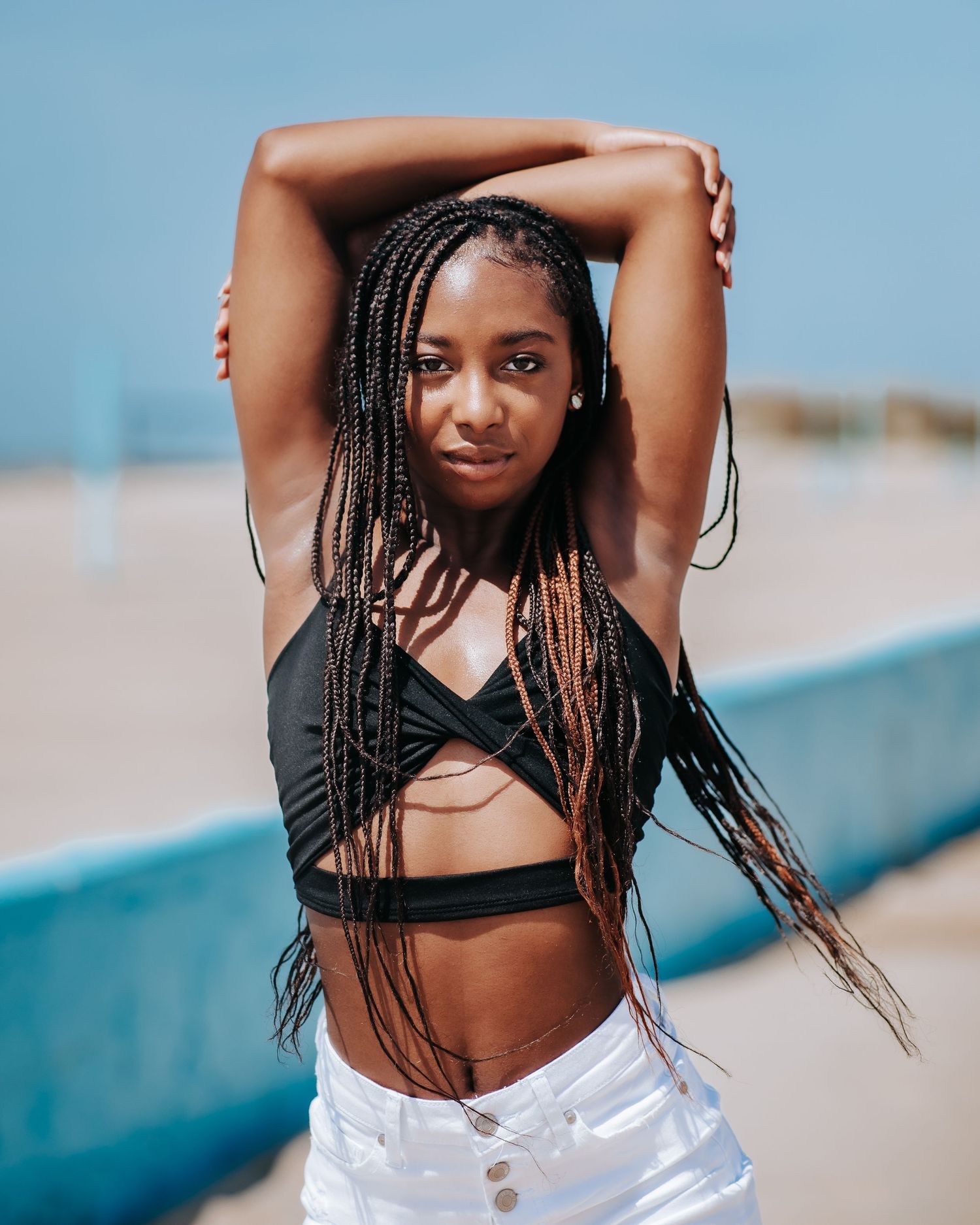 Athletic figure with braids poses confidently in black workout attire.