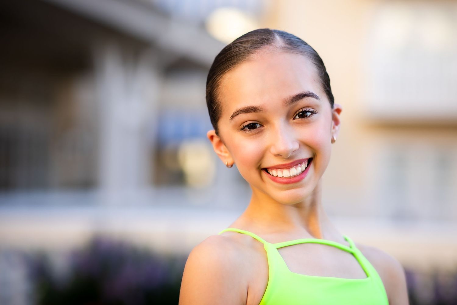 Joyful portrait of a dancer in a neon green top with a bright genuine smile.