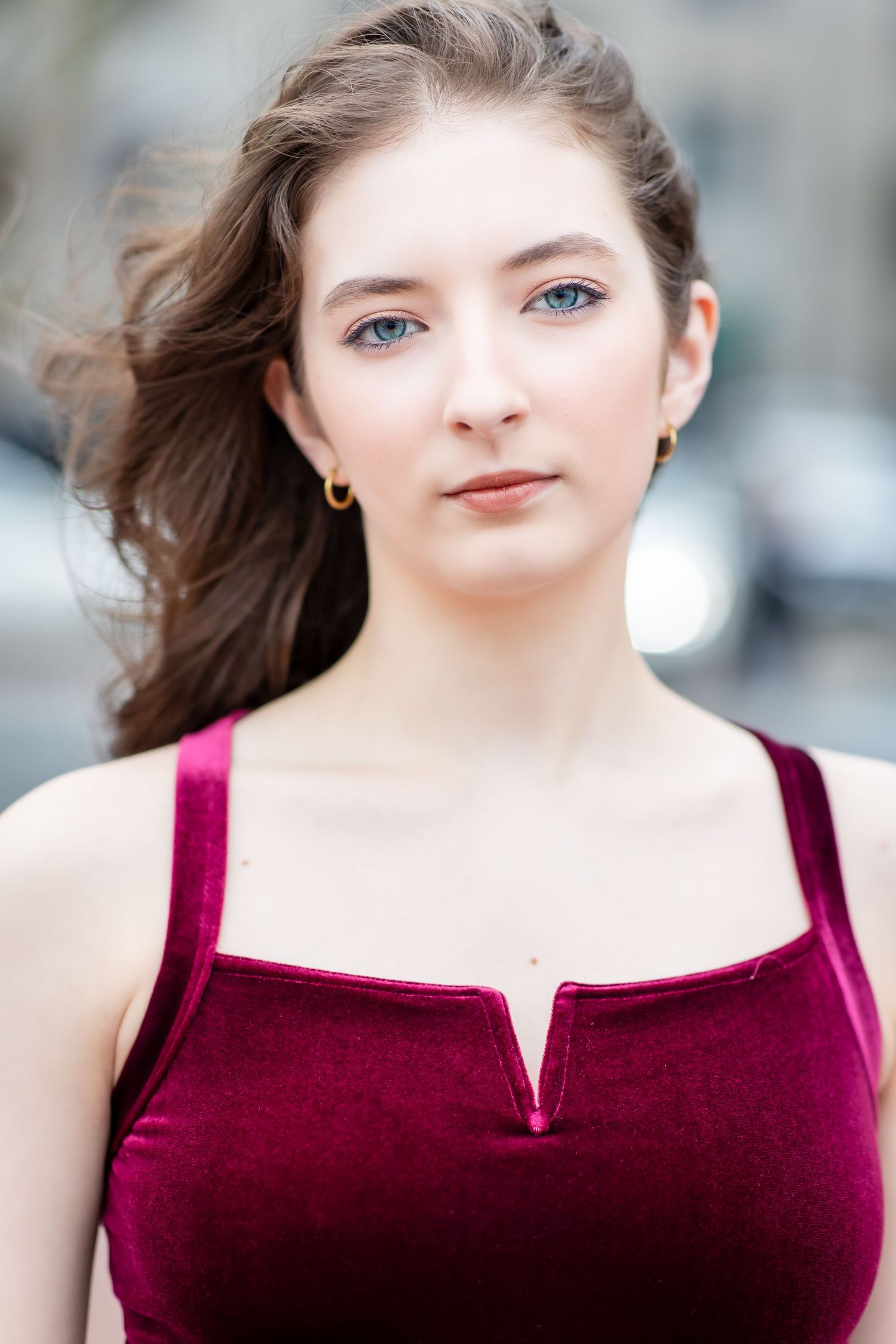 Portrait featuring someone in a burgundy velvet top against a soft blurred background.
