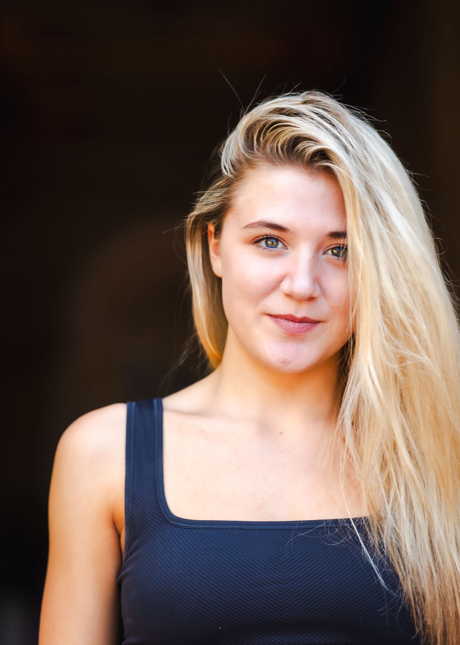 Portrait against dark background with dramatic side lighting.