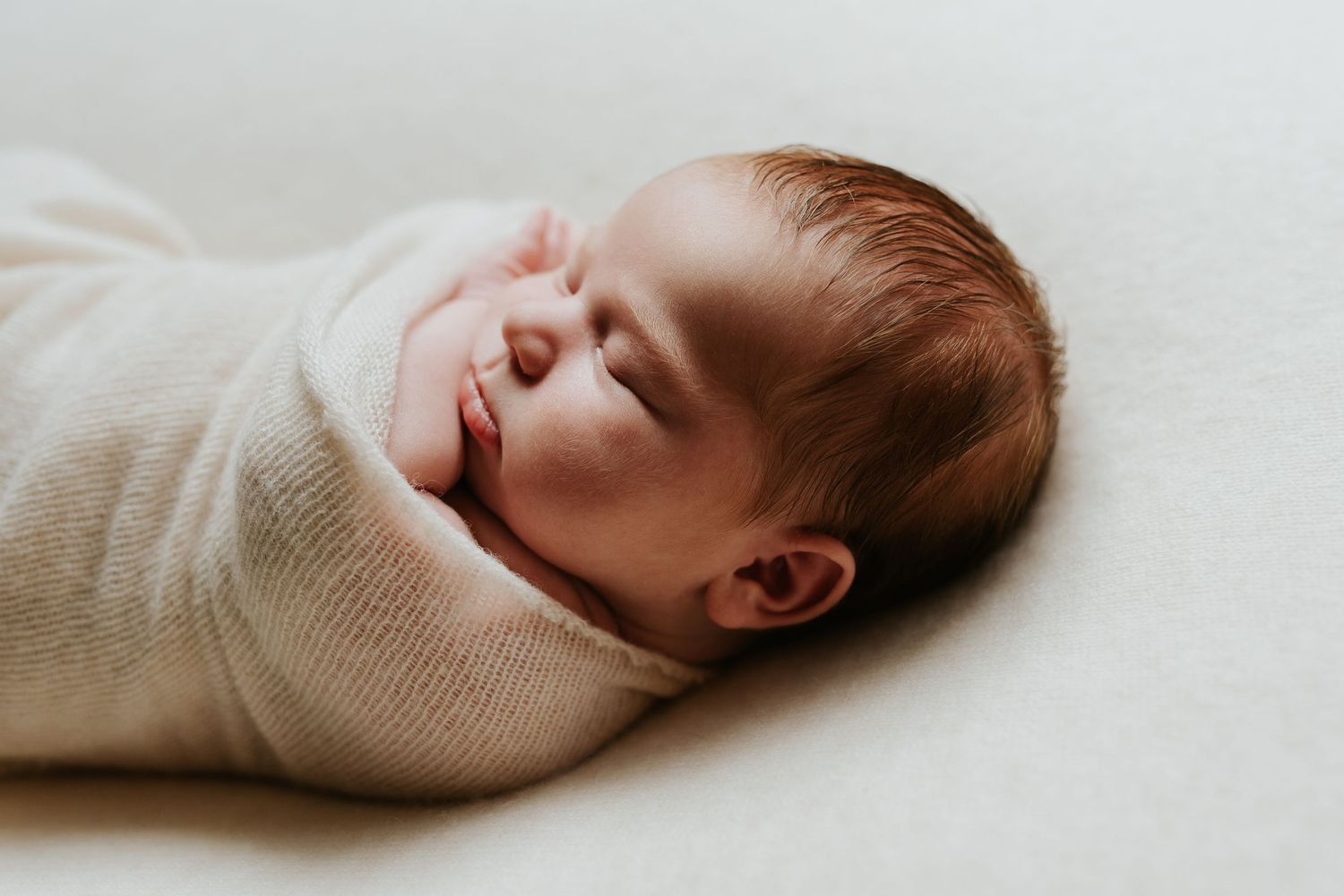 Newborn baby wrap in cream blanket sleeping