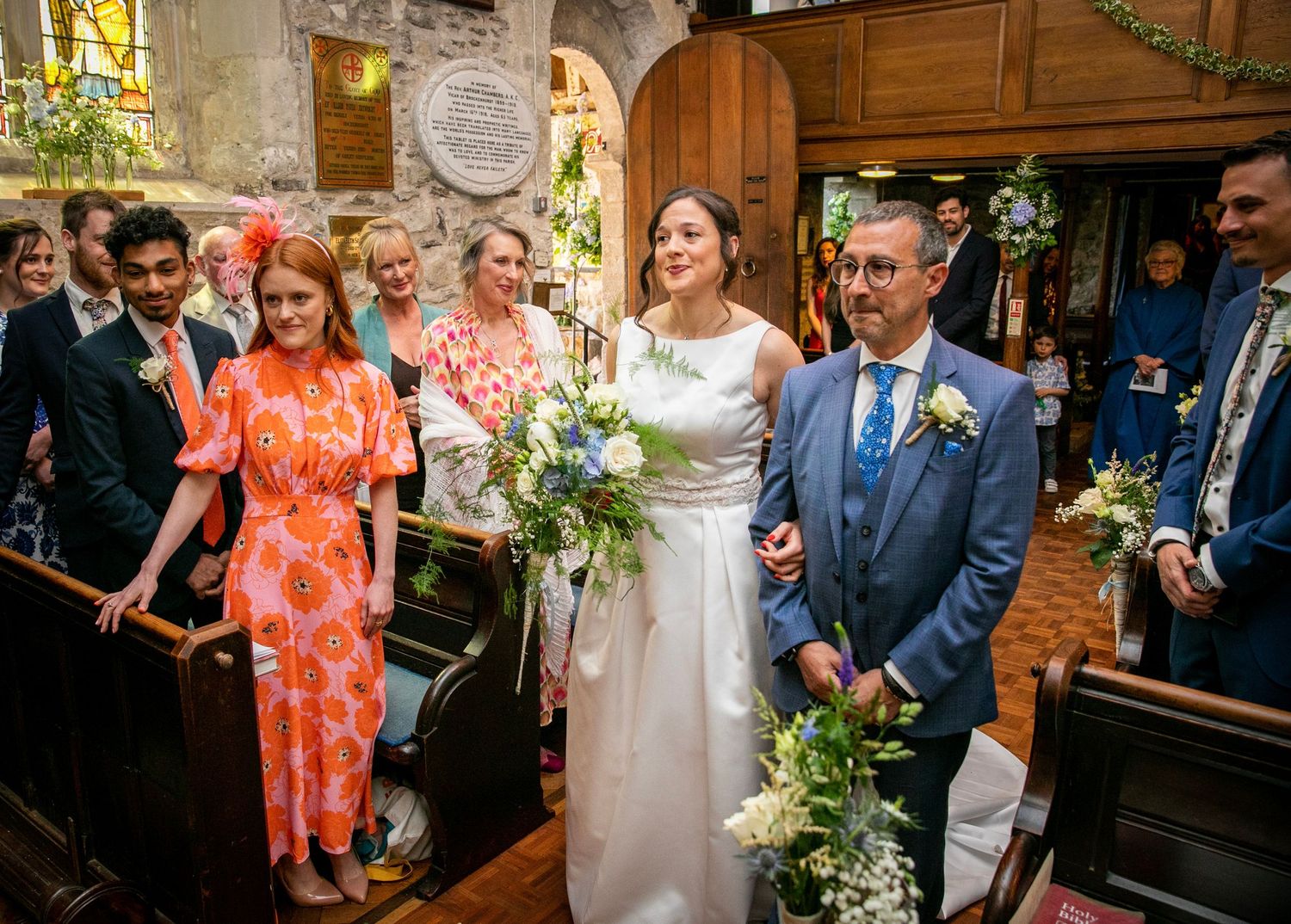 Wedding ceremony in a traditional church decorated with floral arrangements and greenery.