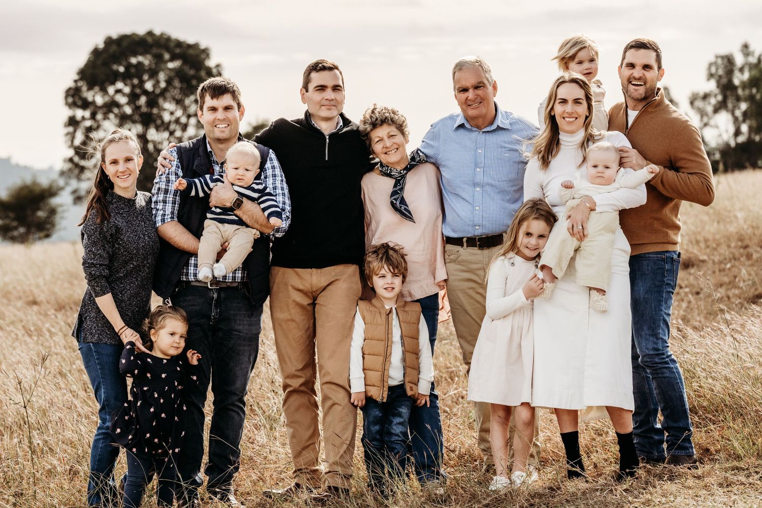 A large family group posing together on a grassy hillside during golden hour.