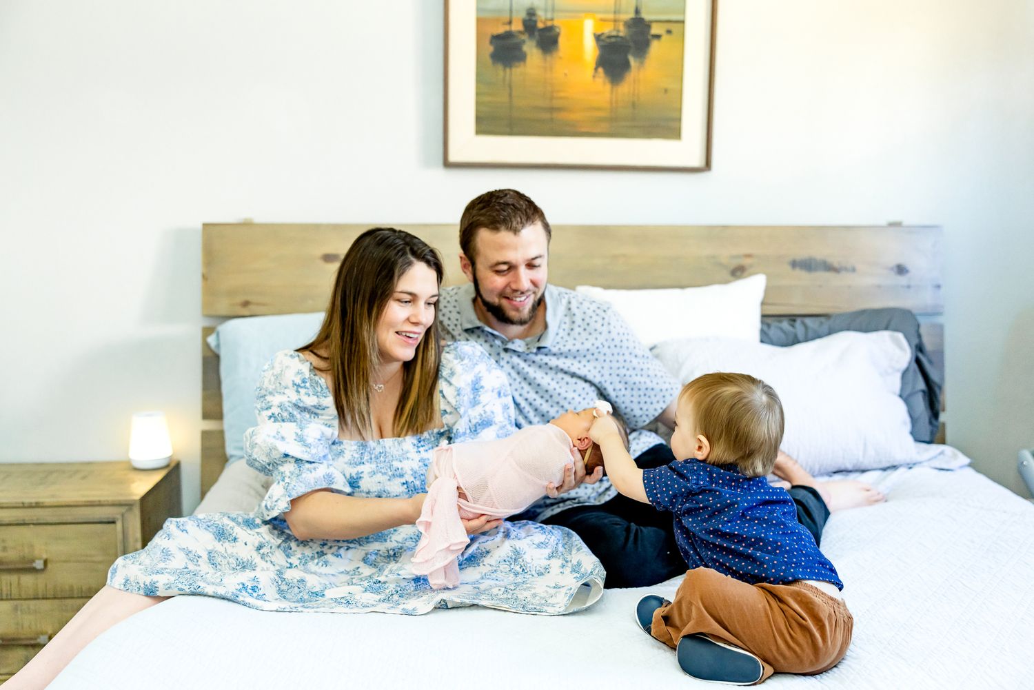 Toddler boy touches his new sister while parents smile during newborn photos in Colorado Springs.