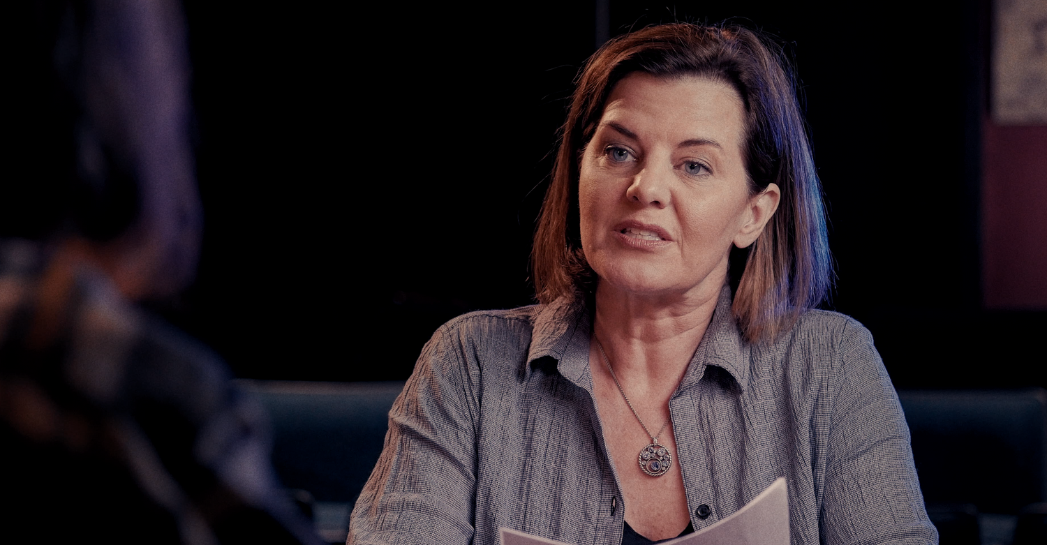 Woman speaking during dimly lit interview setting.