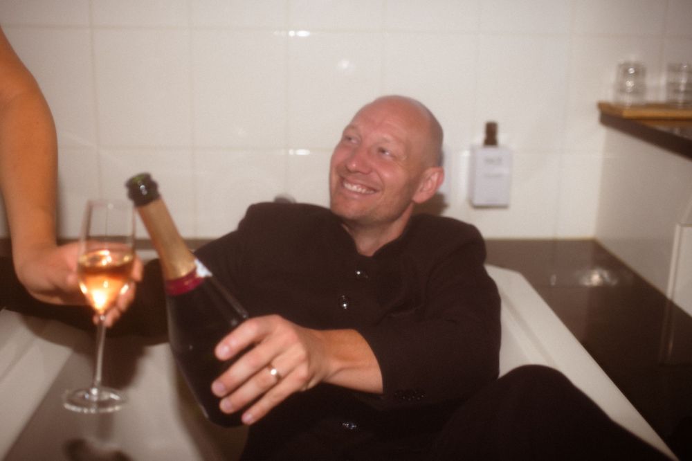 Couple celebrates with champagne in stylish bathroom setting.