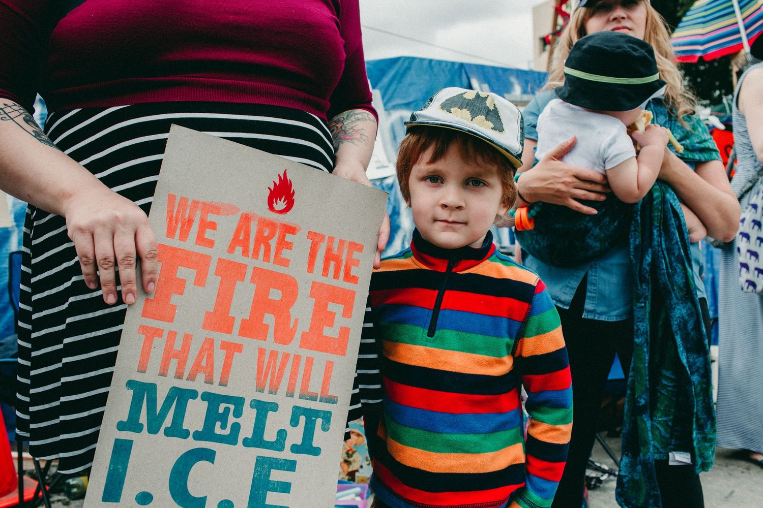 small child stands with parent holding WE ARE THE FIRE THAT WILL MELT ICE sign portland oregon photojournalism