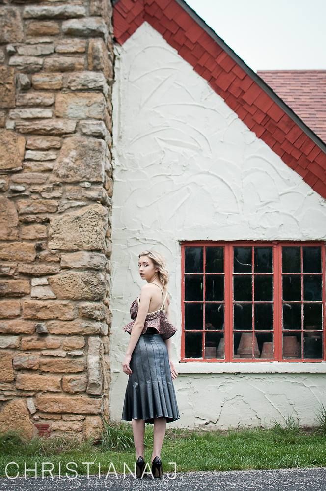 Fashion photo against stone building with pleated skirt and vintage architectural elements.