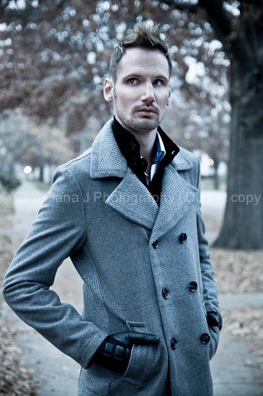 Professional fashion photo of model in grey wool peacoat posing outdoors in autumn setting.
