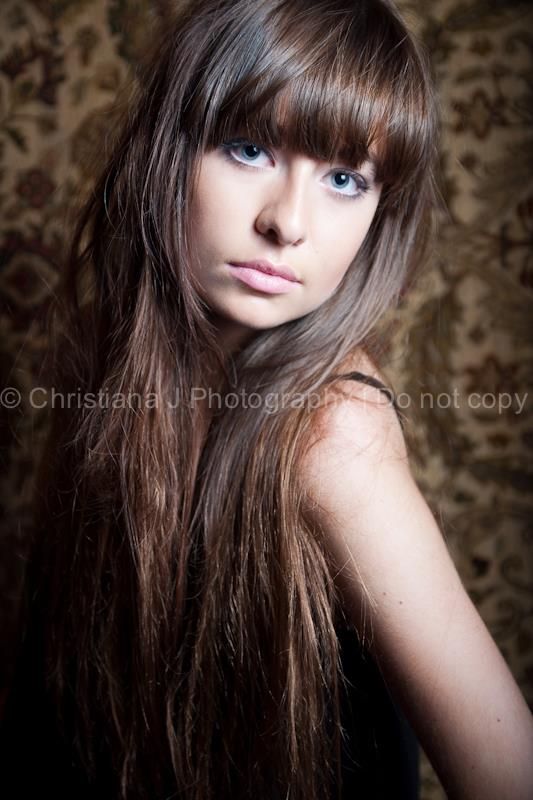 Beauty portrait against textured wallpaper featuring long brown hair and dramatic makeup.