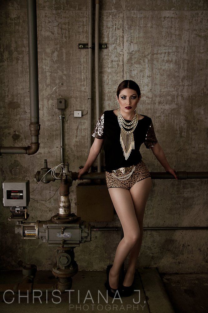 Editorial fashion portrait in industrial setting with model wearing sequined outfit and pearls.