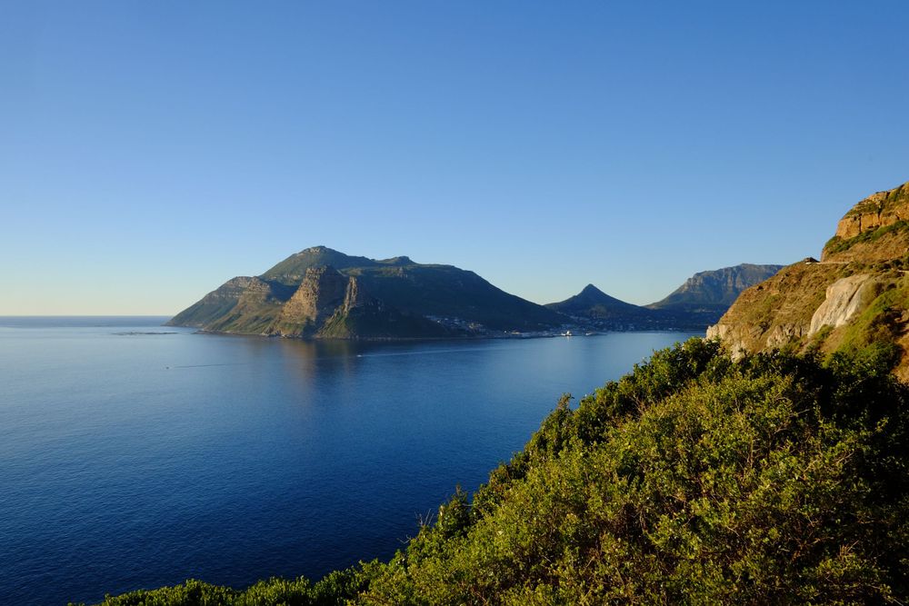Dramatic coastal mountain scenery along Chapman's Peak Drive overlooking a tranquil blue ocean bay.