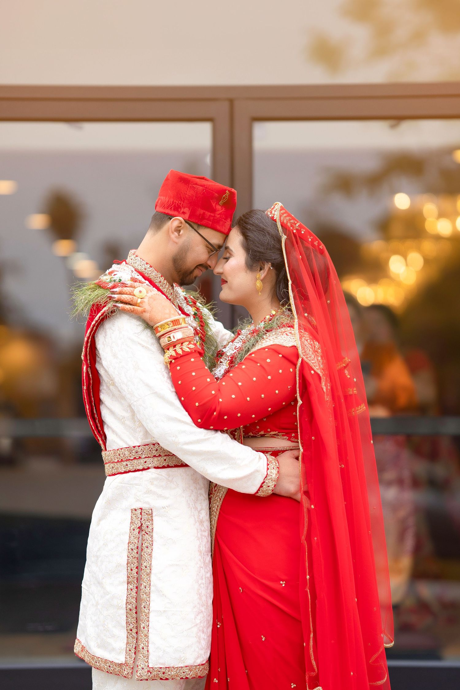 A romantic moment between newlyweds in traditional South Asian wedding attire at dusk.