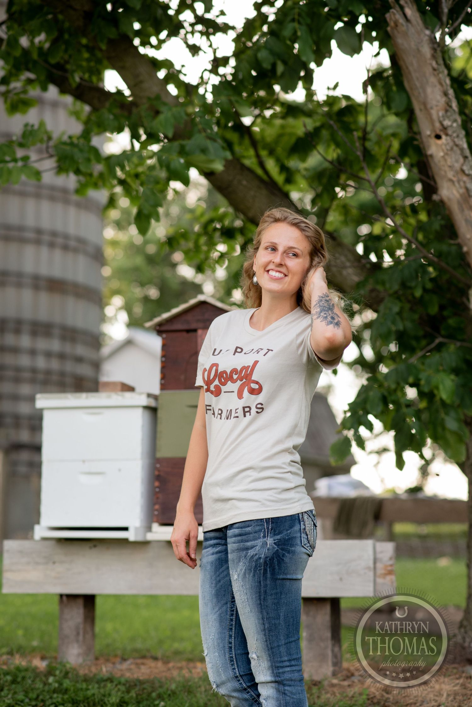 A casual outdoor scene with white beehive boxes under leafy green trees.