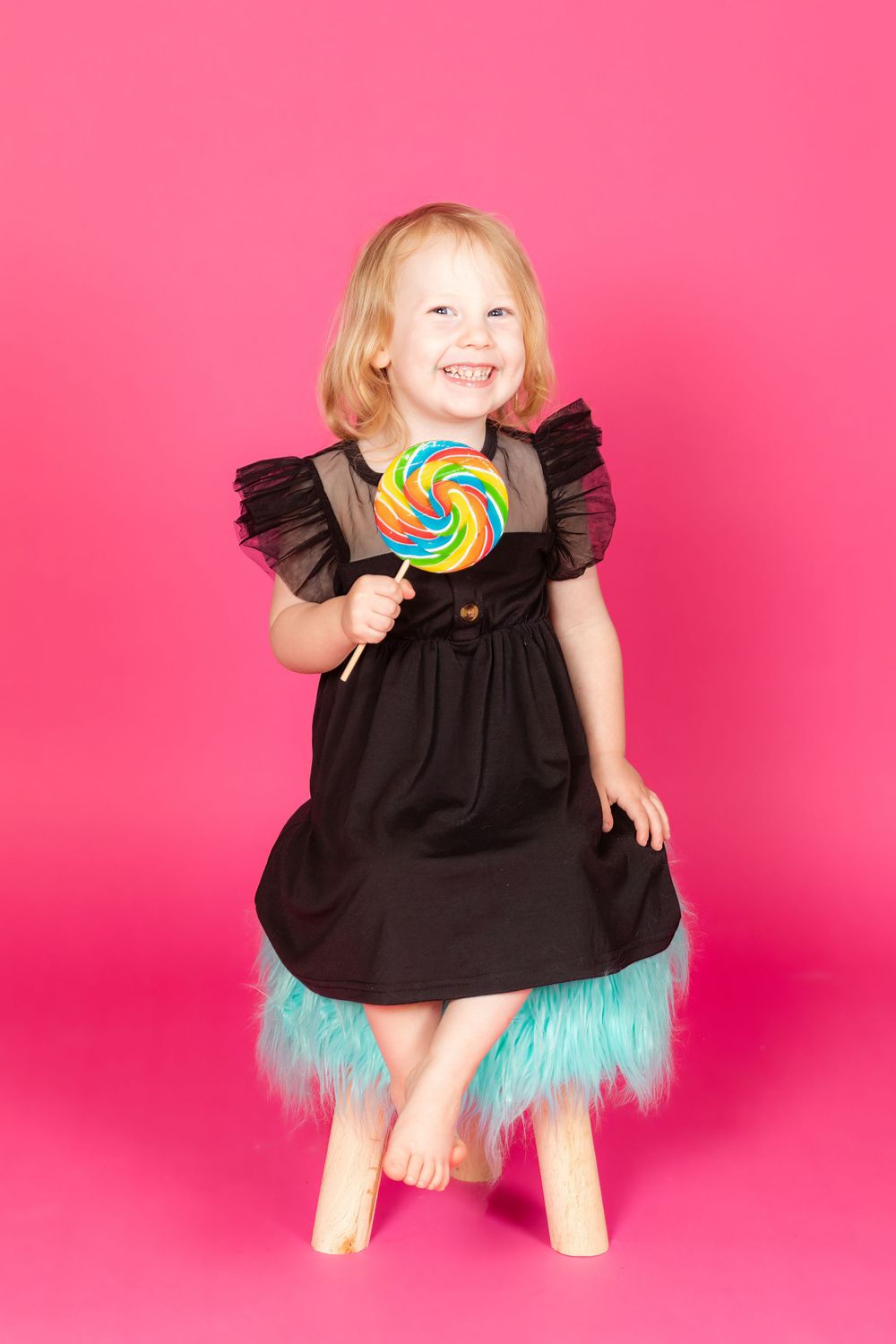 little girl in black dress sitting on teal stool on savage tulip pink backdrop in studio clayton new jersey gloucester