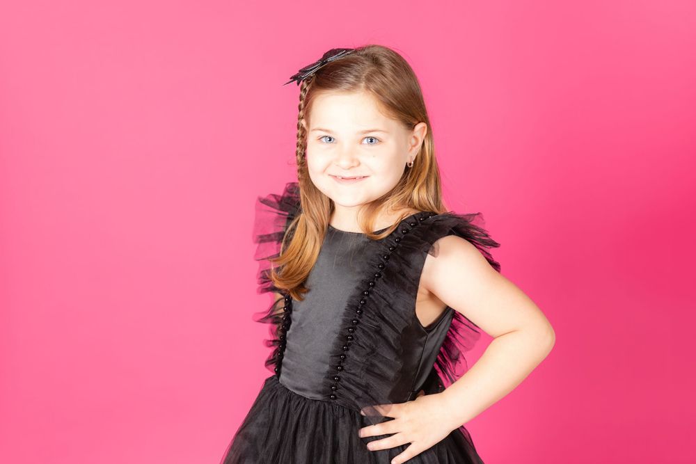 little girl in black dress sitting on teal stool on savage tulip pink backdrop in studio clayton new jersey gloucester