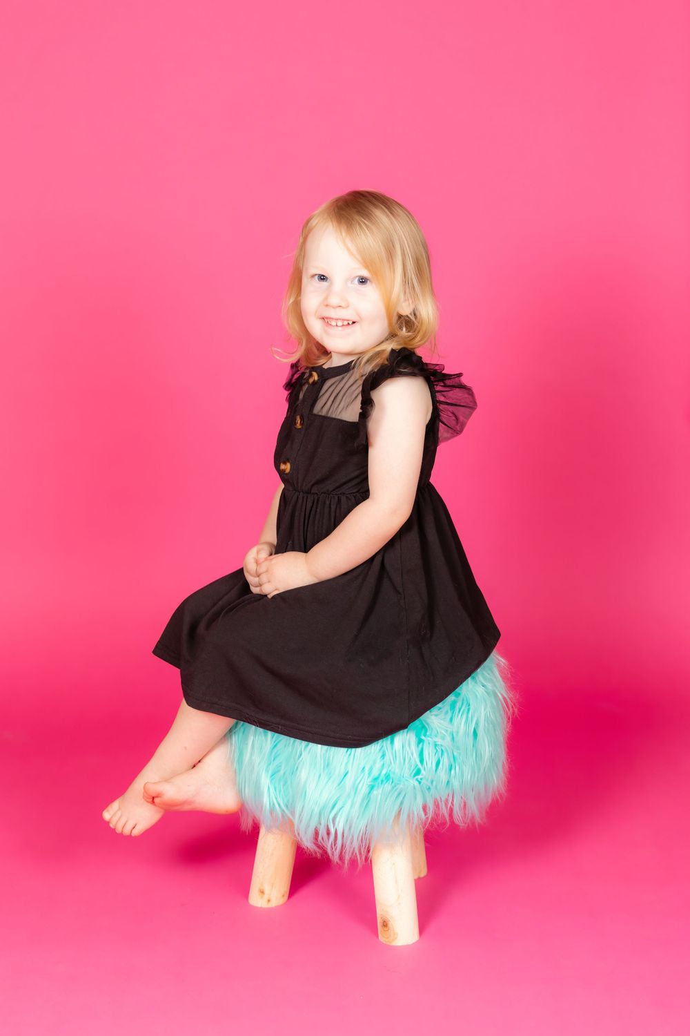 little girl in black dress sitting on teal stool on savage tulip pink backdrop in studio clayton new jersey gloucester