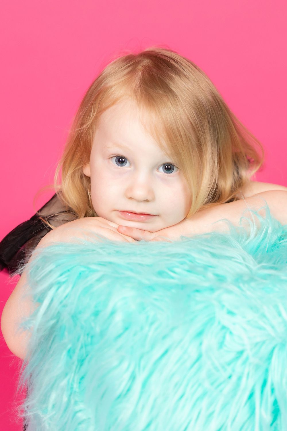 little girl in black dress sitting on teal stool on savage tulip pink backdrop in studio clayton new jersey gloucester