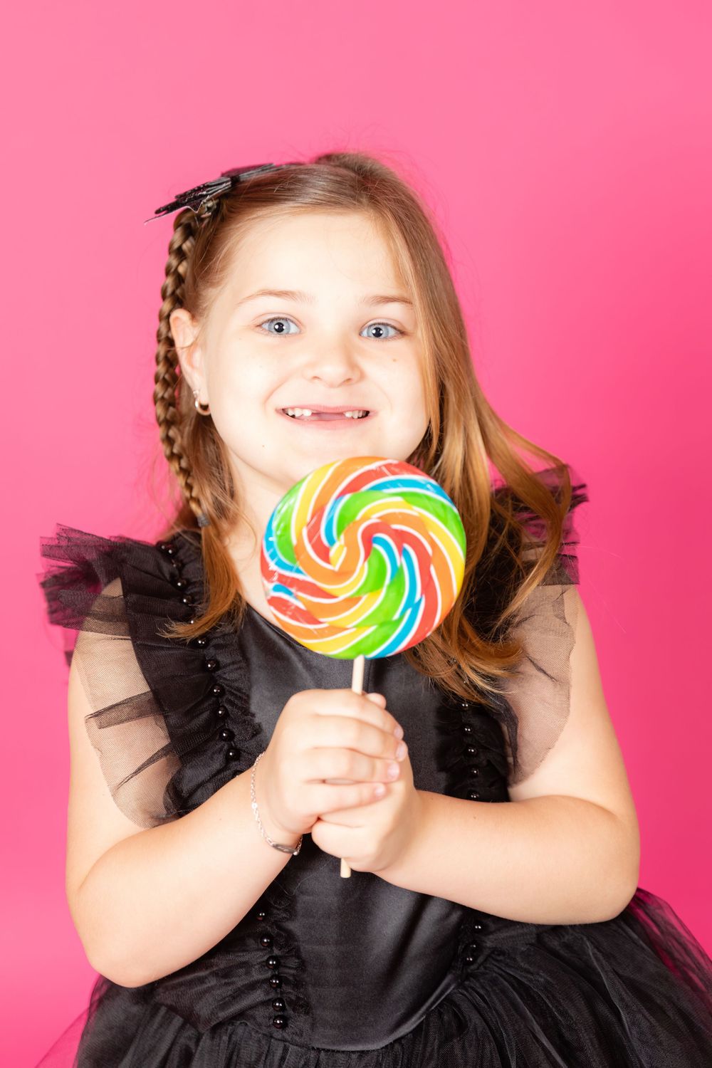 little girl in black dress with bright lollipop on savage tulip pink backdrop in studio clayton new jersey gloucester