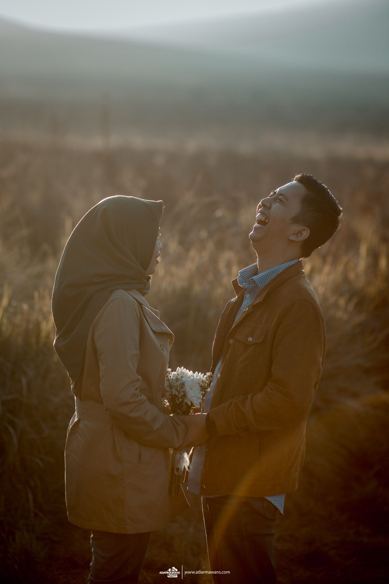 Romantic couple sharing intimate moment in golden wheat field during sunset.