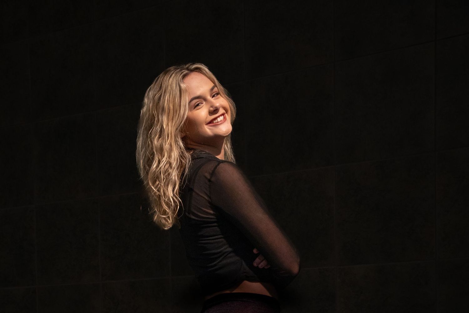 Portrait of a woman in black against dark background with dramatic lighting.