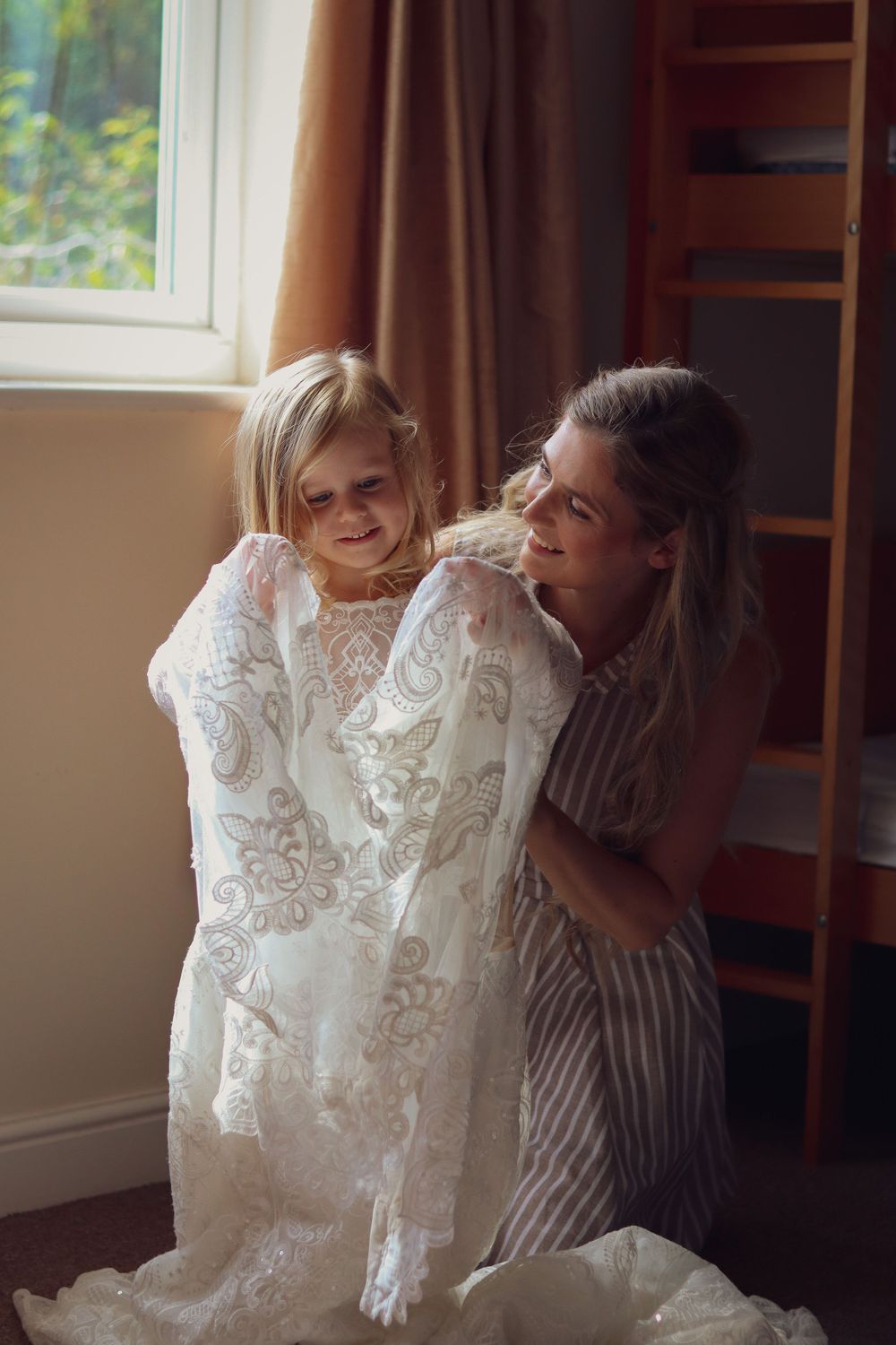 A touching moment as someone tries on a delicate white lace wedding dress.