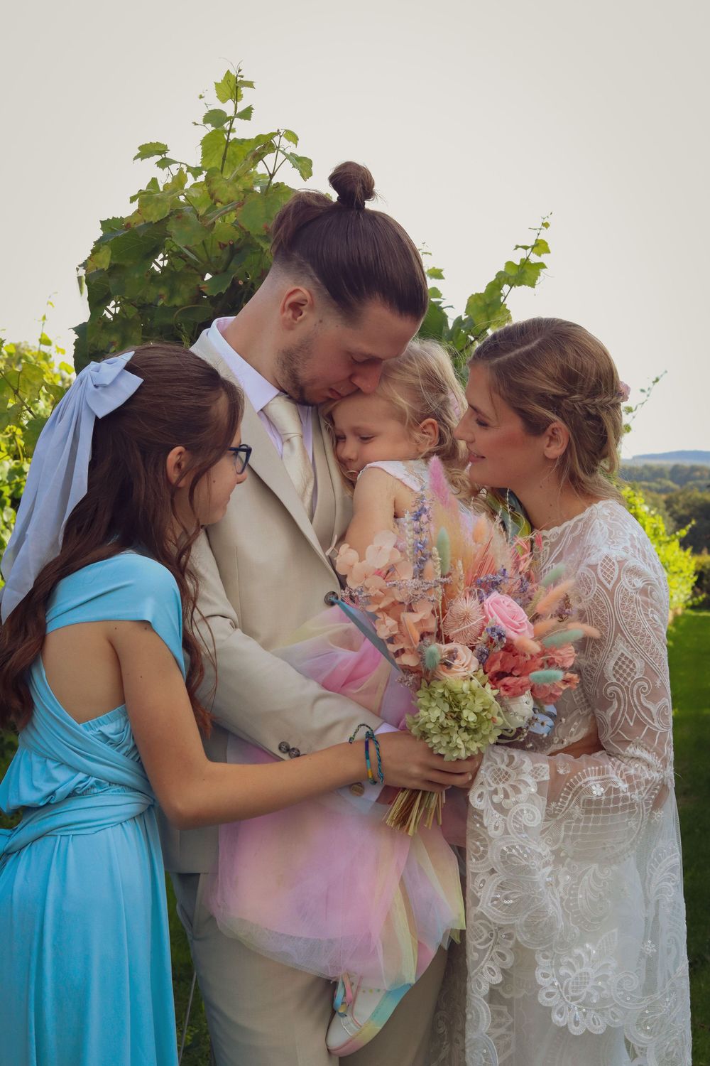 A tender family moment shared during a wedding celebration in a vineyard setting.