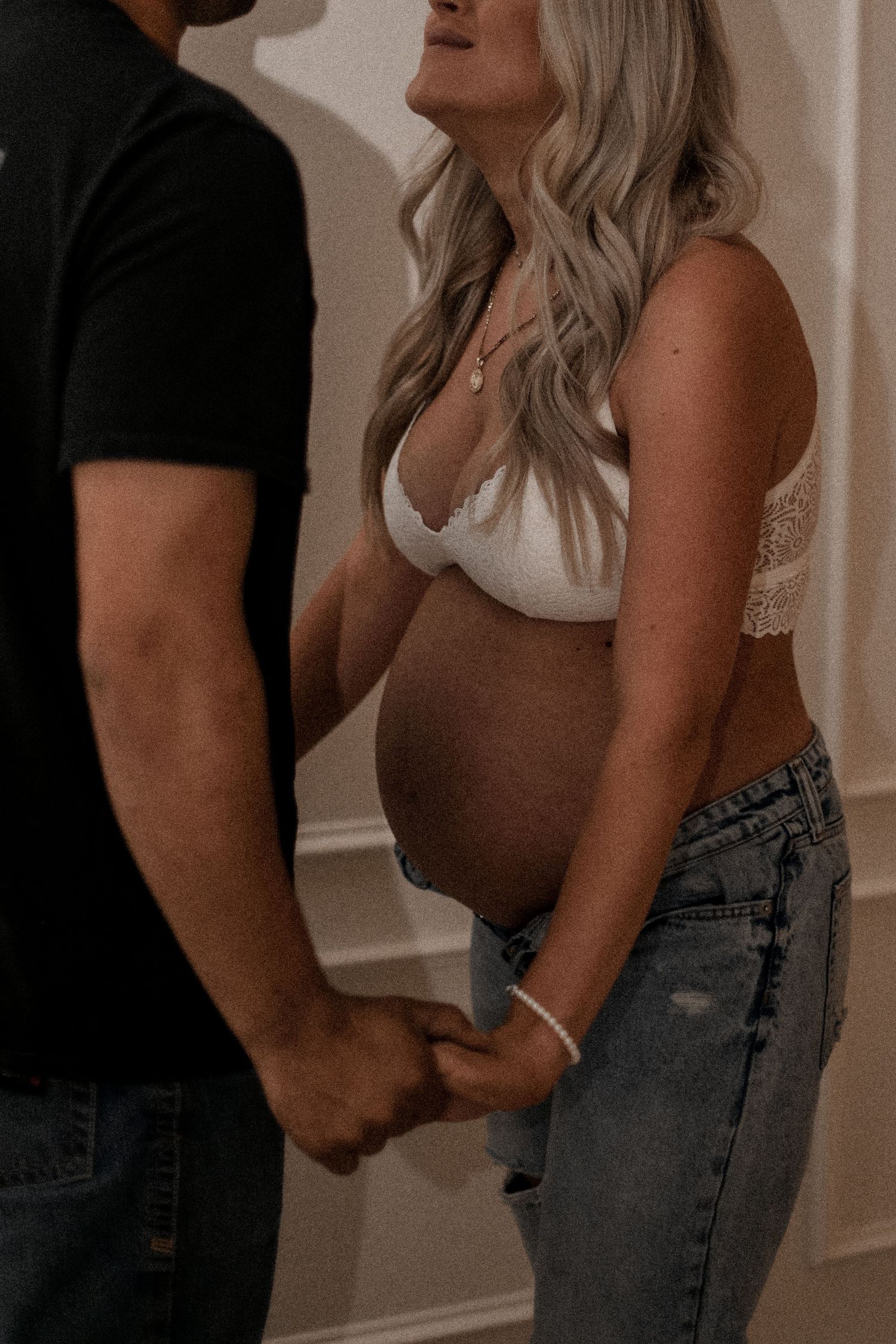 An intimate maternity moment captured in soft indoor lighting.