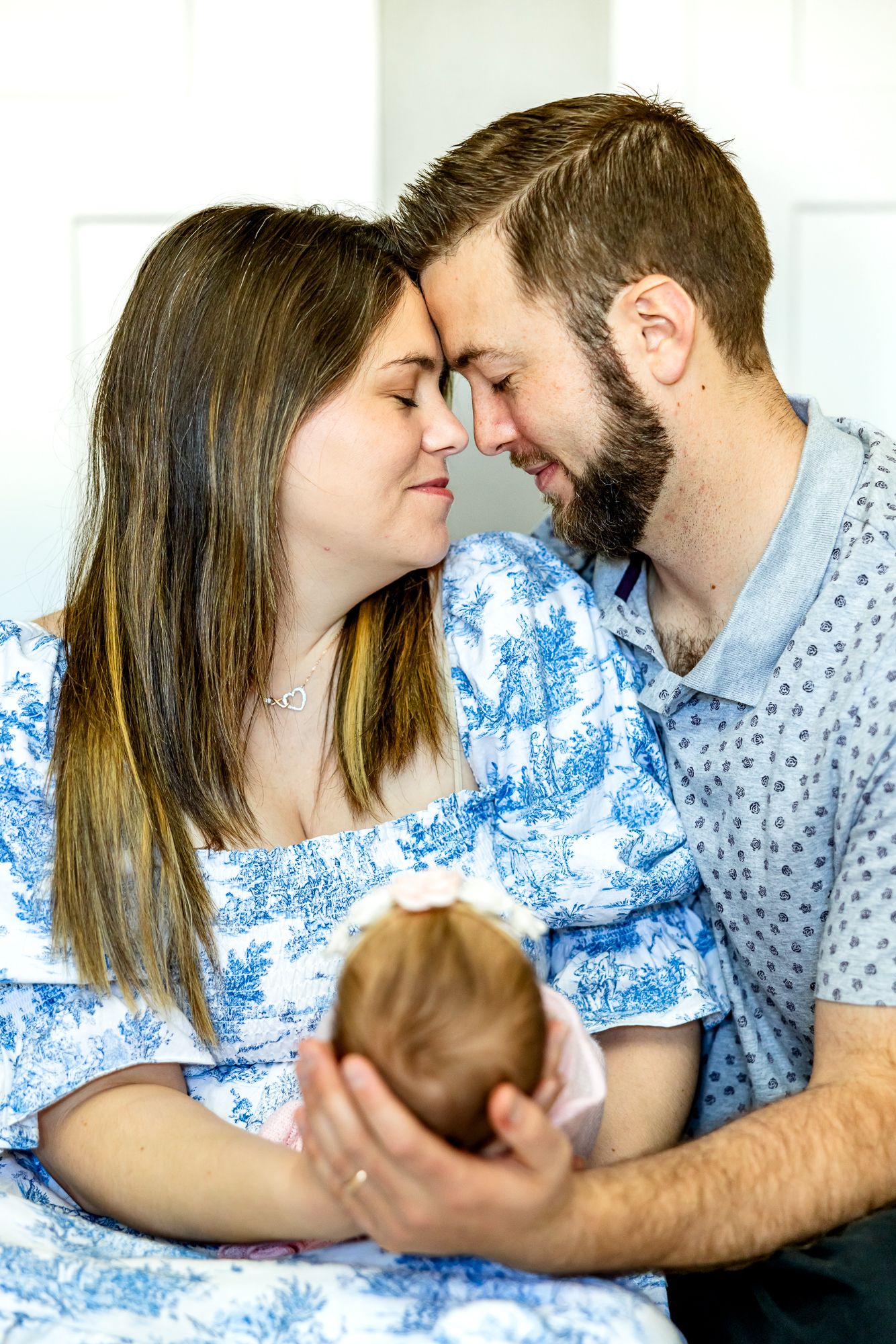Parents hold their new baby girl and touch foreheads eyes closed during newborn photos in Colorado Springs.