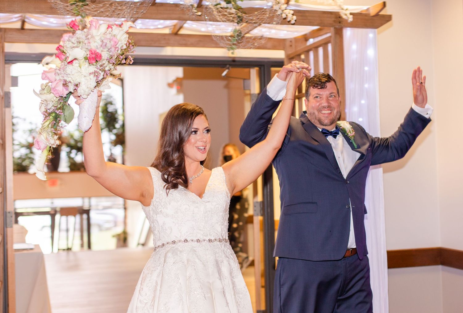 Wedding celebration scene with wooden beams and floral decorations in natural lighting.