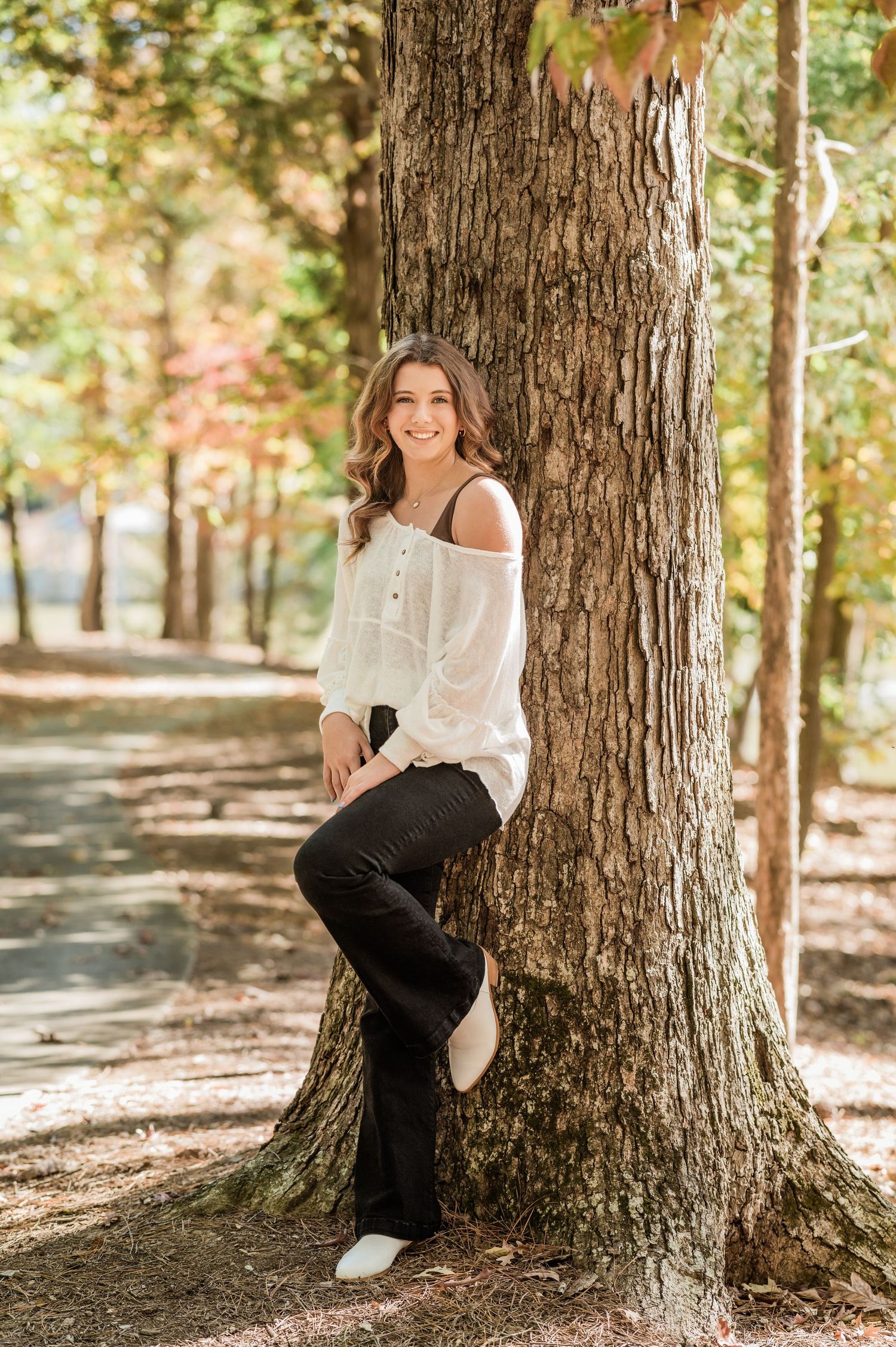 White sweater outfit photographed against large tree trunk in dappled sunlight.
