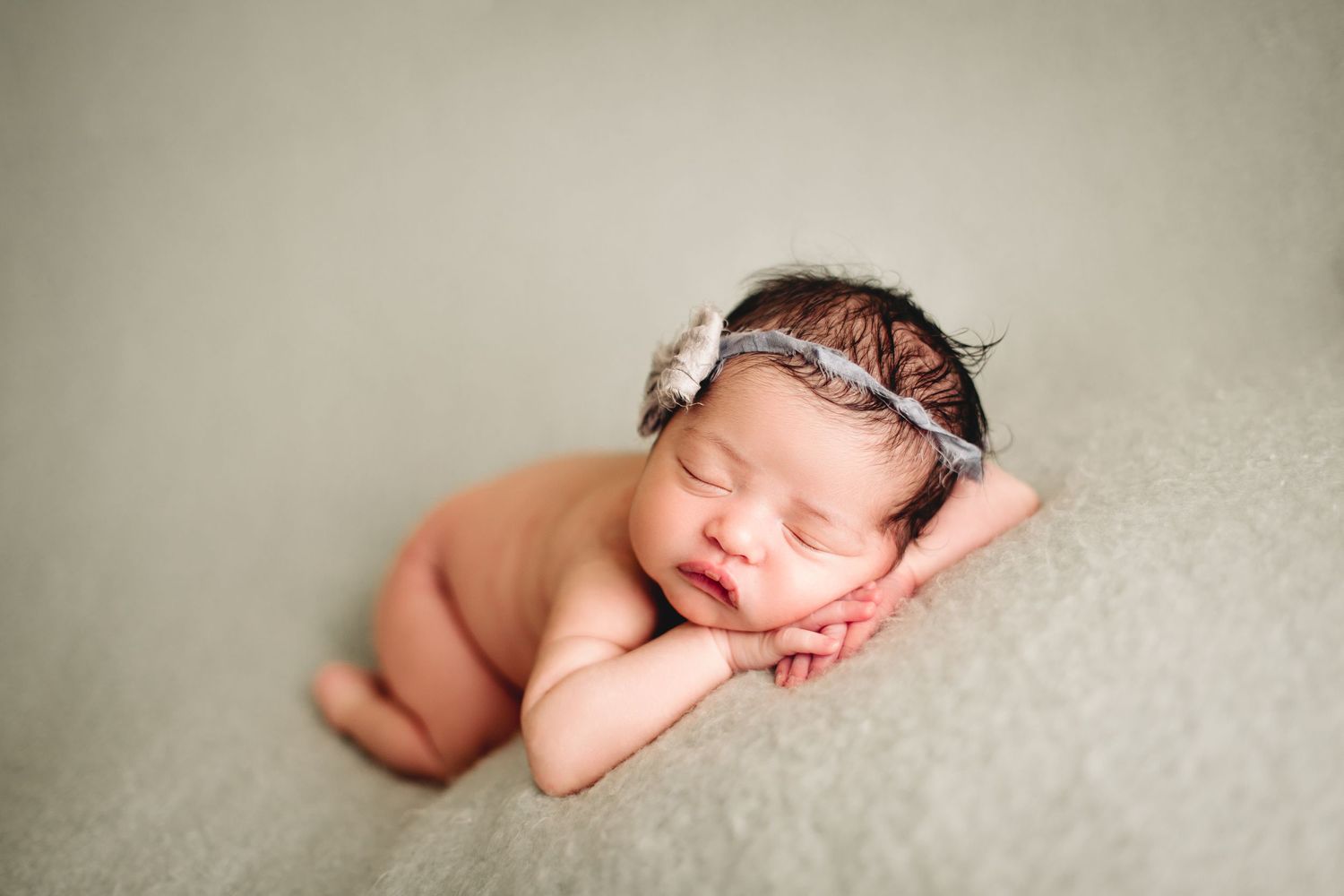 infant posed laying on tummy with chin resting on hands