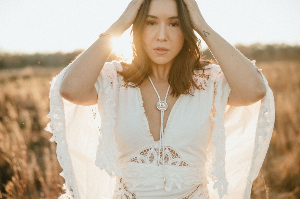 A dreamy portrait in white lace dress with sunlit field backdrop.