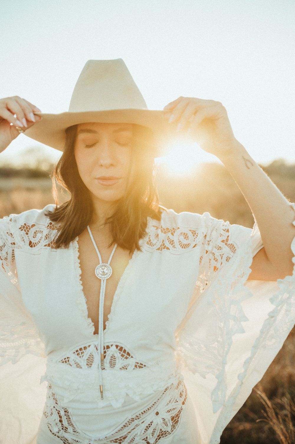 Ethereal sunlit photography with white lace dress and western hat.