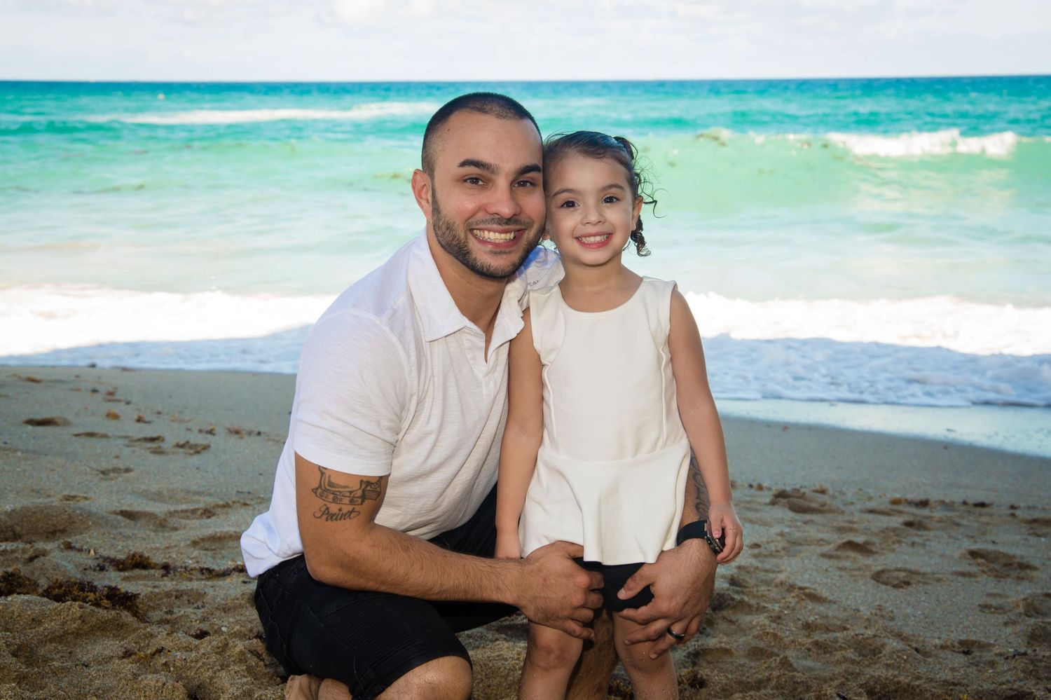 Beach photoshoot with beautiful turquoise ocean waves and sandy shoreline.