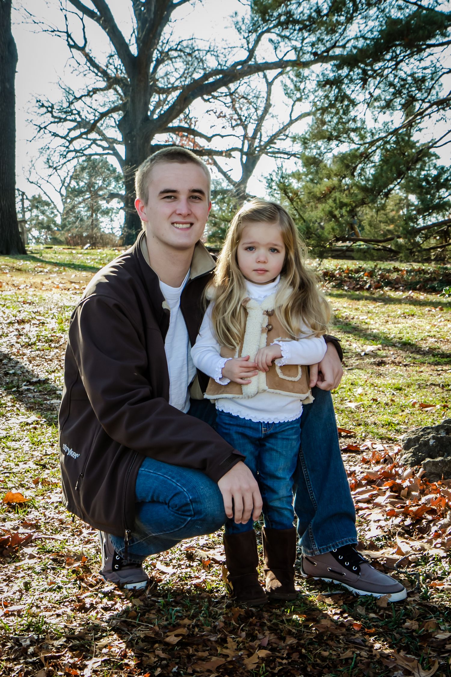 Father and daughter portrait in a fall setting with autumn leaves on the ground.