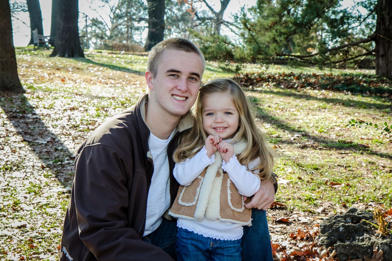 Parent and child sitting together outdoors in an autumn park setting.