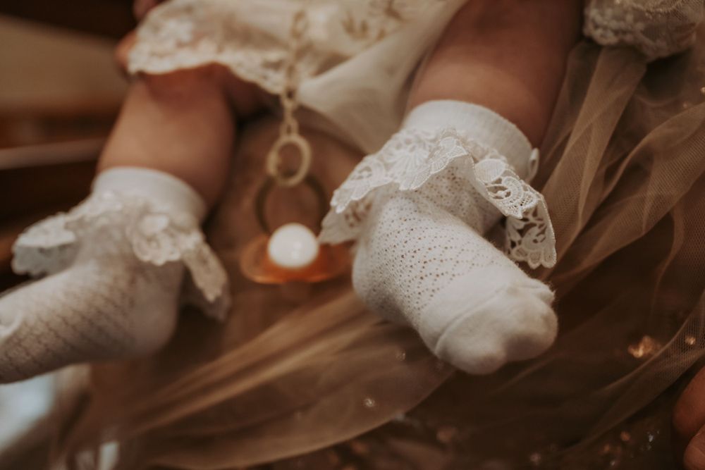 Detail shots of white lace baptismal clothing and delicate baby accessories.