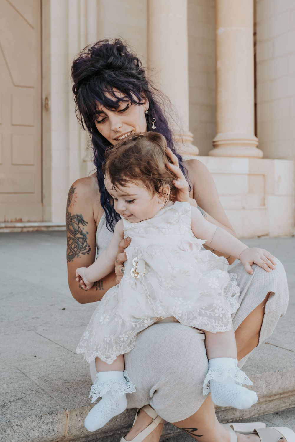 Sweet candid moment between mother and child wearing matching white outfits.