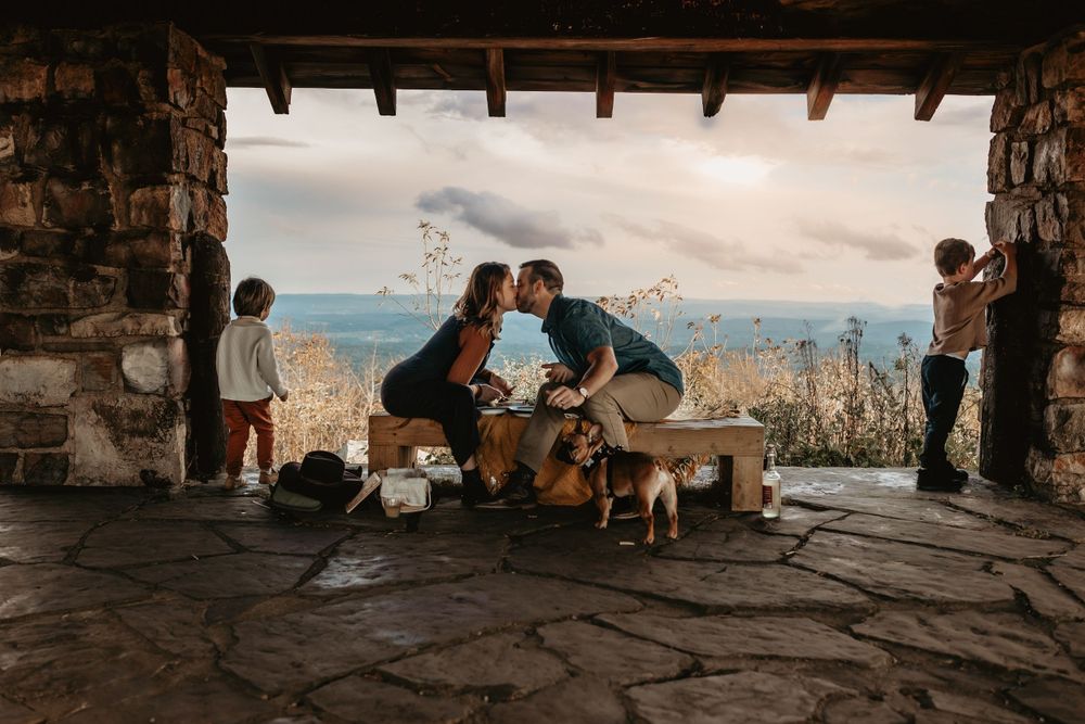 Family and dog gathering at stone overlook with mountain vista.