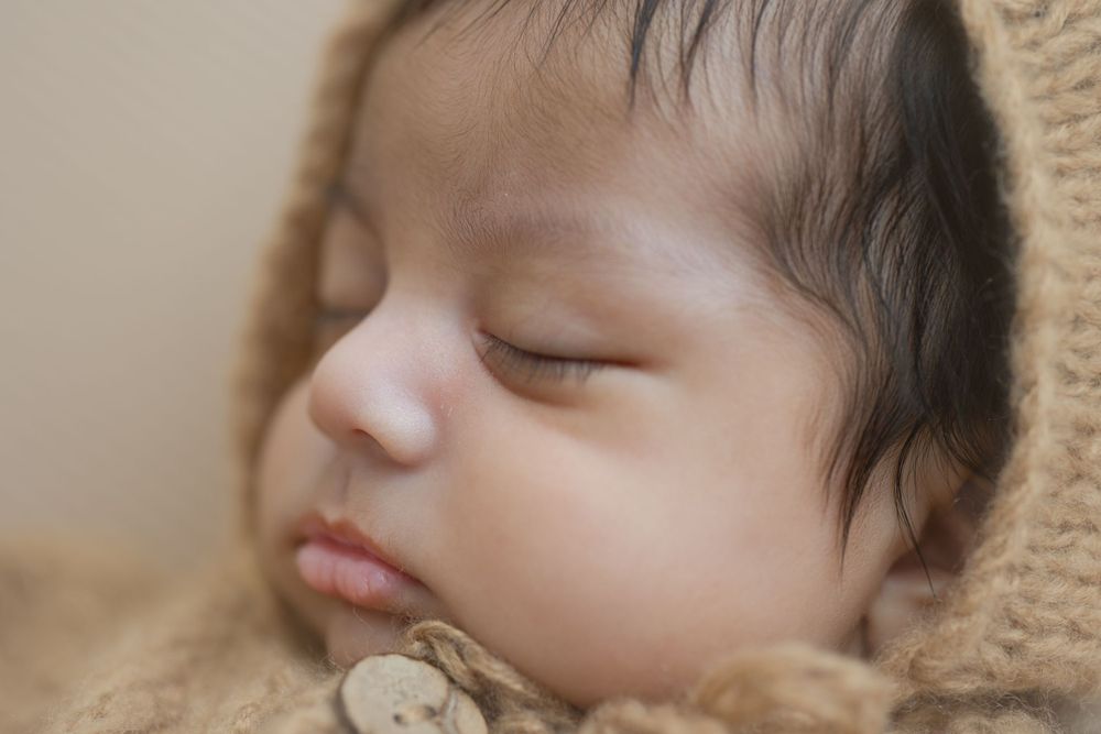 Sleeping baby wrapped in soft beige blanket in peaceful portrait.