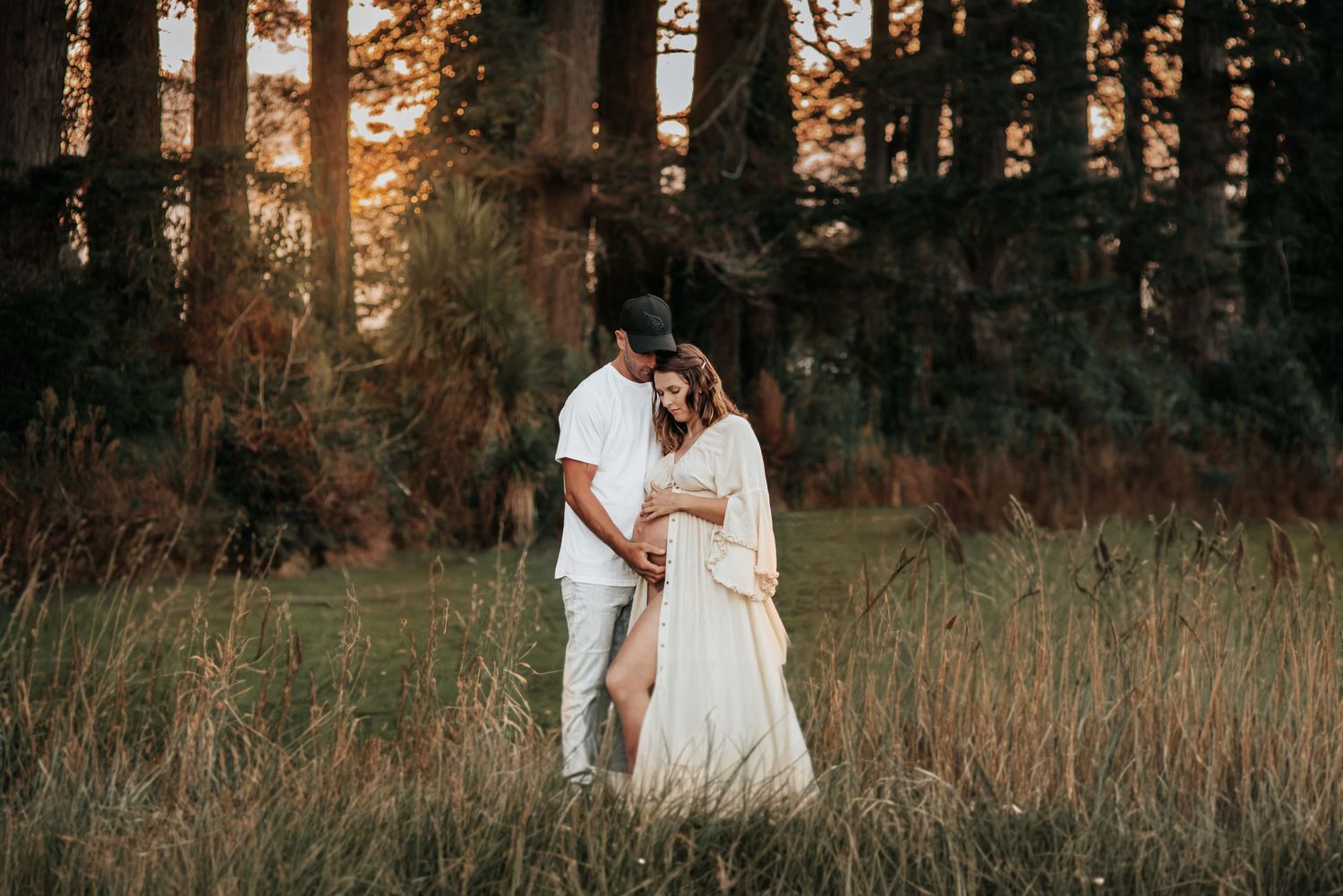 Romantic sunset maternity photo in a forest clearing.