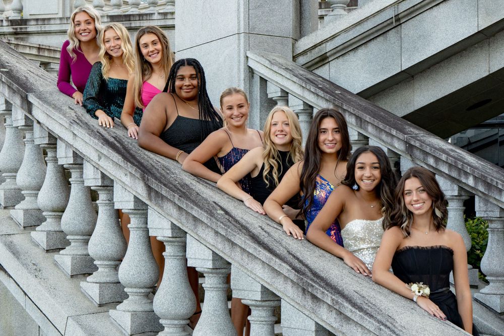 Friends in formal attire lined up diagonally on elegant stone steps for a photo shoot.