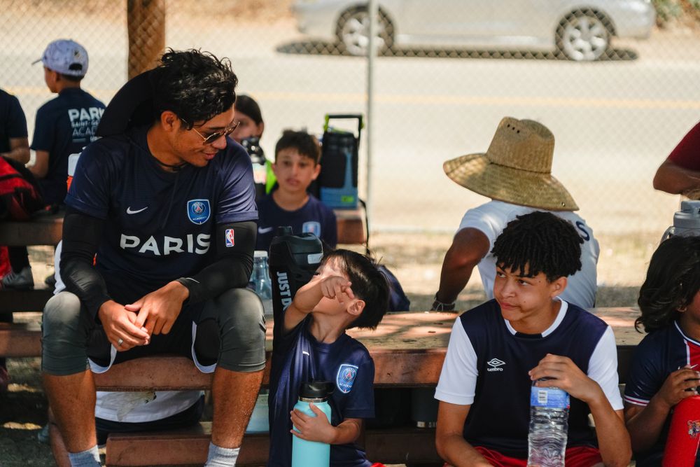 Soccer team members and coaches taking a water break during outdoor practice session.