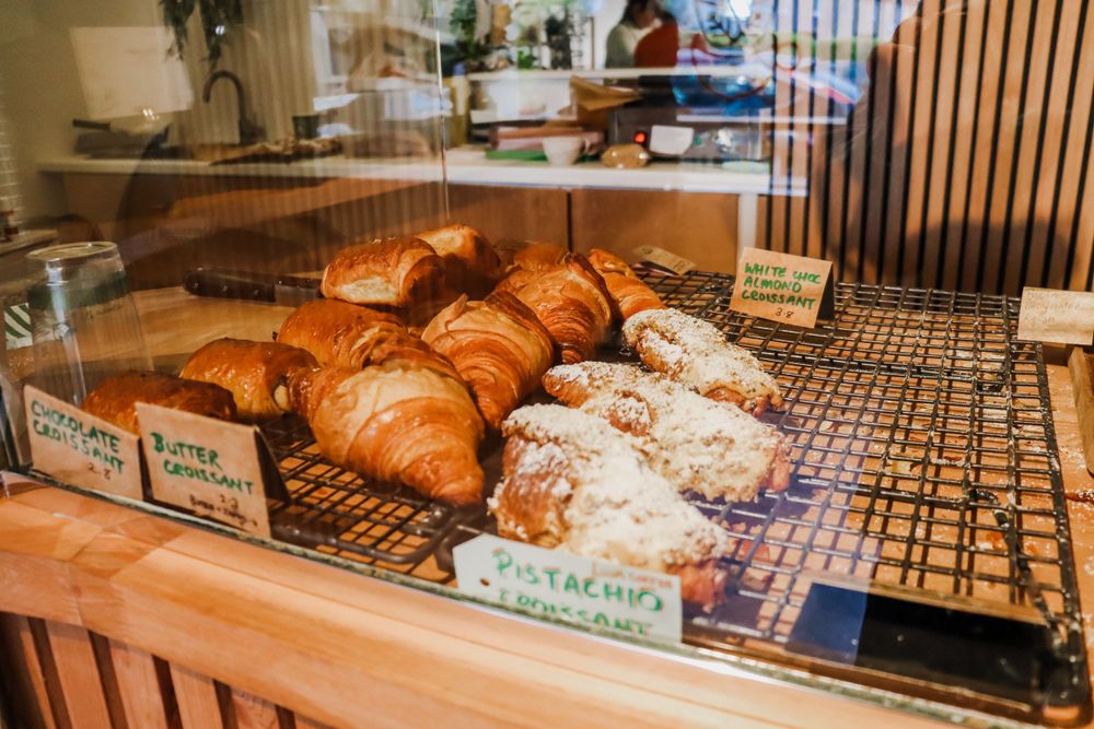 Fresh baked croissants and pastries displayed on a wooden bakery counter.